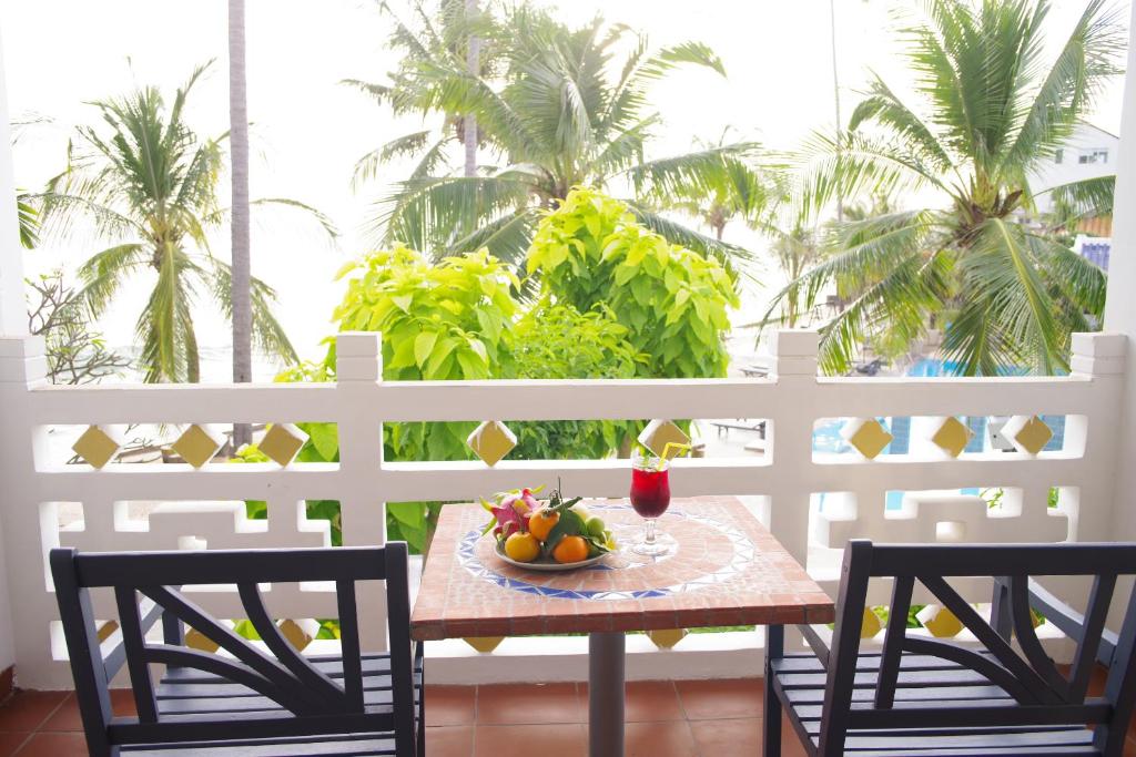 Terase ar skatu uz palmu dārzu, kur uz galda ir augļu plate un dzēriena glāze. Ideāla vieta relaksācijai un atpūtai.