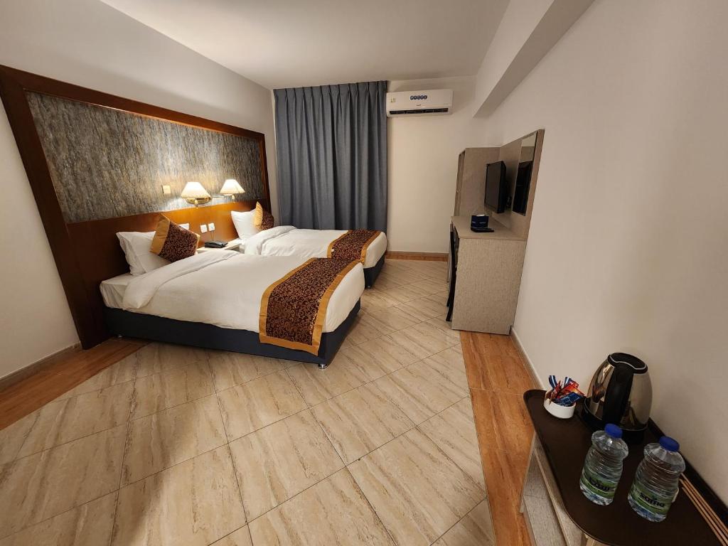 Mūsdienīgs viesnīcas numurs ar divām gultām, televizoru un mini bāru, kā arī ērtu sēdvietu un dabiskiem apgaismojuma akcentiem.