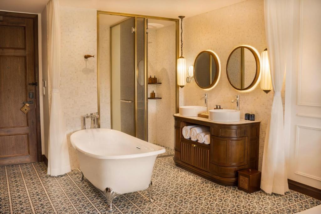 Mūsdienīgs vannas istabas interjers ar brīvstāvošu vannu, divām izlietnēm un elegantu flīžu grīdu. Svaiga un gaisīga atmosfēra ar stilīgiem apgaismojuma elementiem.