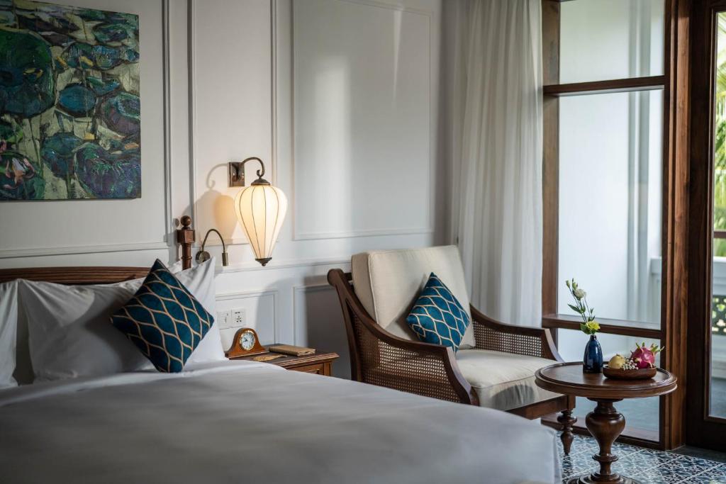 Mūsdienīga guļamistaba ar elegantu interjeru, kas ietver mākslas darbu, mēbelēta atpūtas zona un dabiskā apgaismojuma plūsmu. Ideāla vieta relaksācijai un komfortam.