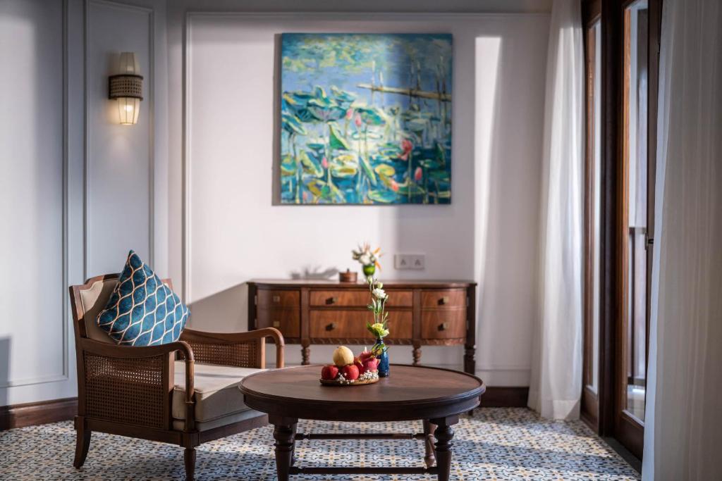 Mūsdienīgs viesistabas stūris ar elegantu krēslu, apaļu galdu un krāšņu gleznu uz sienas, kas attēlo ūdenslilijas. Gaisotne ir mierīga un aicinoša, radot relaksējošu vidi.