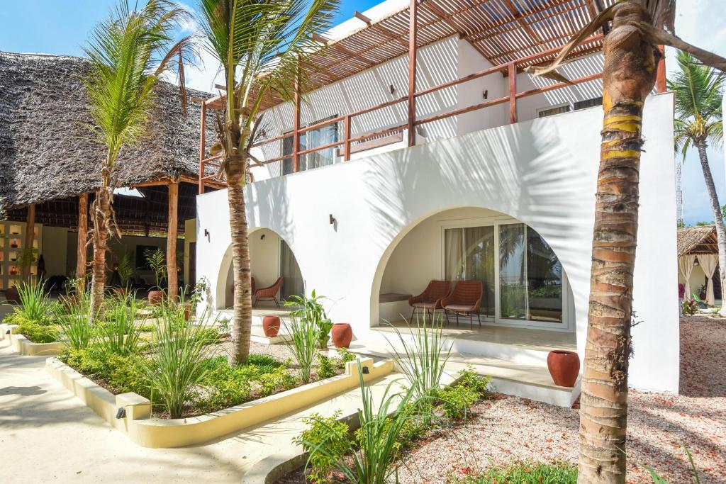 Mūsdienīgs viesnīcas komplekss ar baltām sienām un dabiskām palmām, kas ieskauj skaisti iekārtotu dārzu. Terase ar ērtām atpūtas vietām piedāvā relaksējošu atmosfēru.
