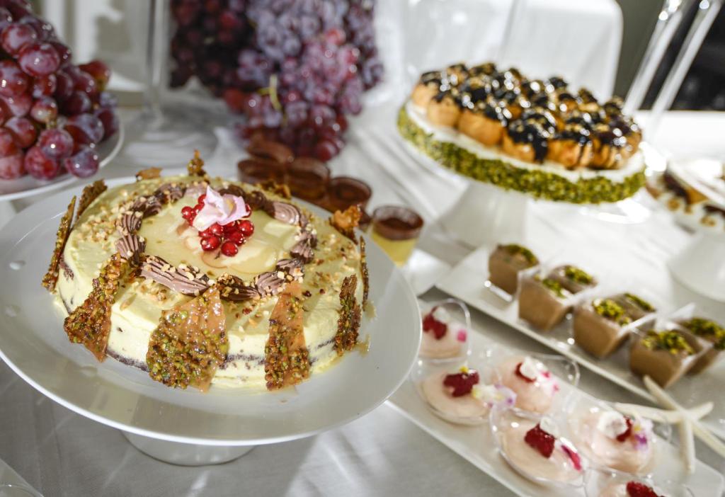 Dekoratīvs kūka ar riekstiem un ogām, apvienota ar dažādiem desertiem un vīnogām, veido izsmalcinātu svētku galdu.