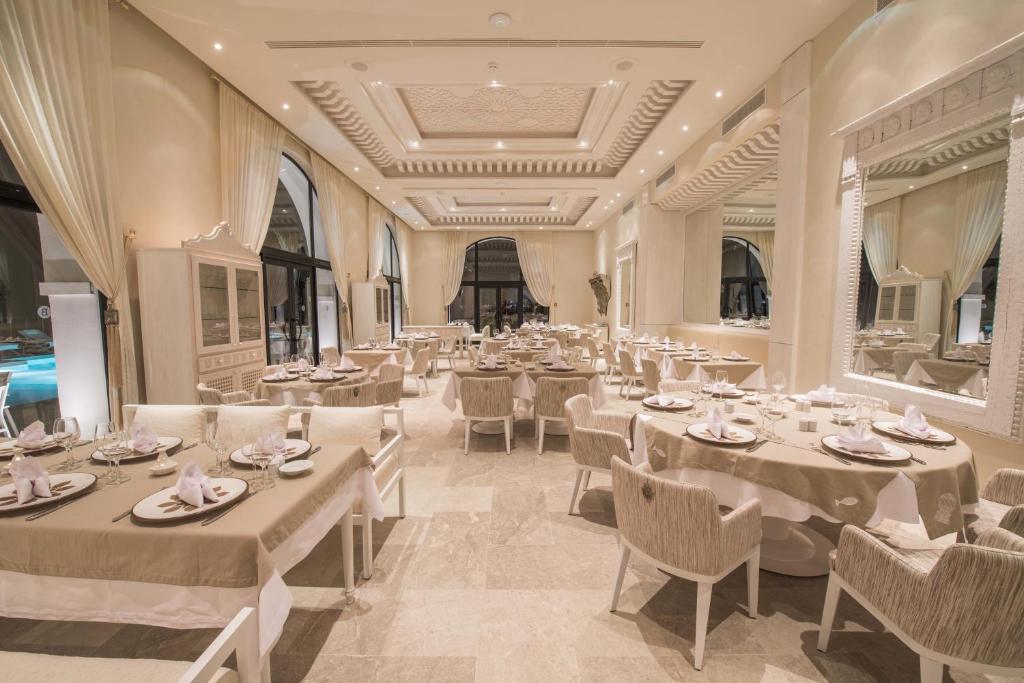 Elegants restorāns ar gaisīgu interjeru, baltiem toņiem un elegantiem galdiem. Plašas logu ailes nodrošina dabīgu apgaismojumu un skatu uz āru.
