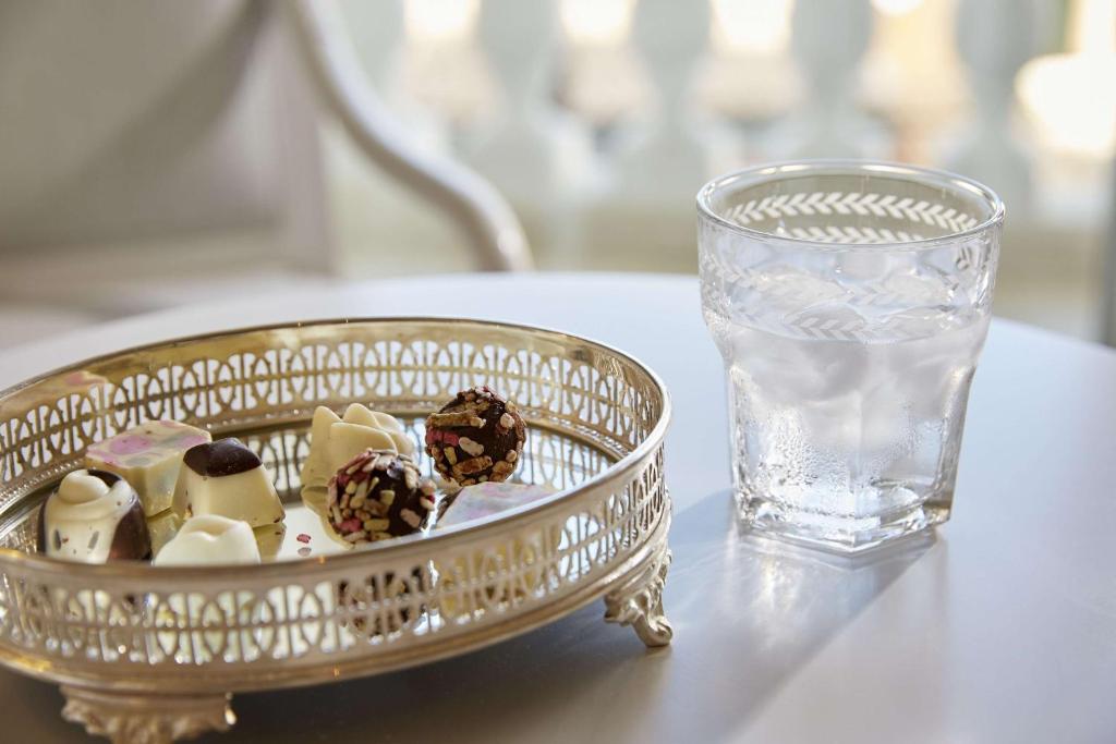Salda konfekte uz sudraba šķīvja blakus glāzei ar ūdeni, radot elegantu un relaksējošu atmosfēru.