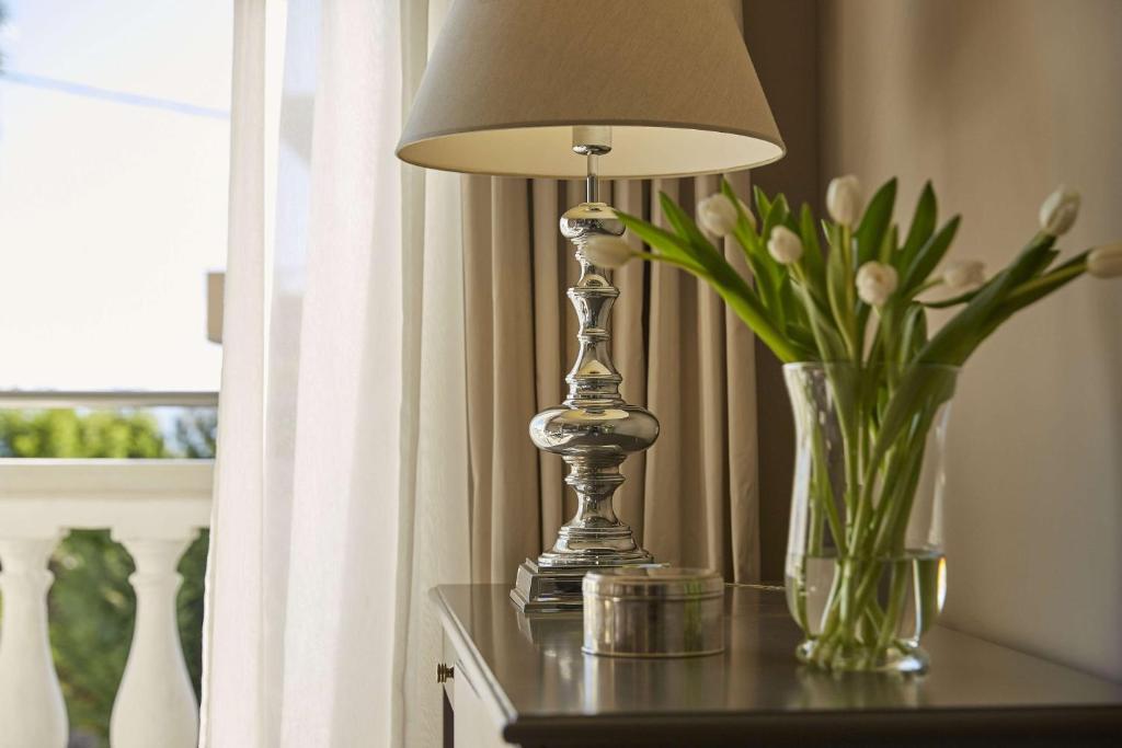 Mūsdienīga interjera apdare ar spīdīgu lampu un ziedu pušķi uz galda, radot siltiem un mājīgiem akcentiem.