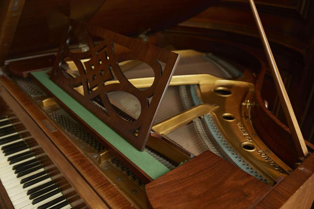 Skaista klavieru iekšpuse ar izsmalcinātu koka detaļu un zeltītu mehānismu, kas atklāj instrumenta eleganci.