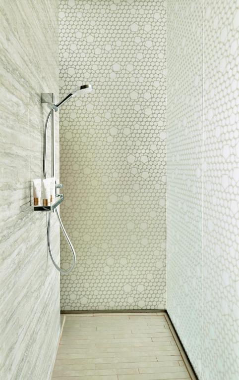 Mūsdienīga duša ar elegantu flīžu dizainu un minimālistisku izskatu, izceļot skaidru un tīru atmosfēru.