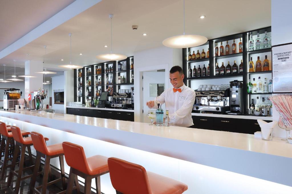 Bāra darbinieks sajauc dzērienus modernā bārā ar stilīgu interjeru un plašu alkoholisko dzērienu izvēli.