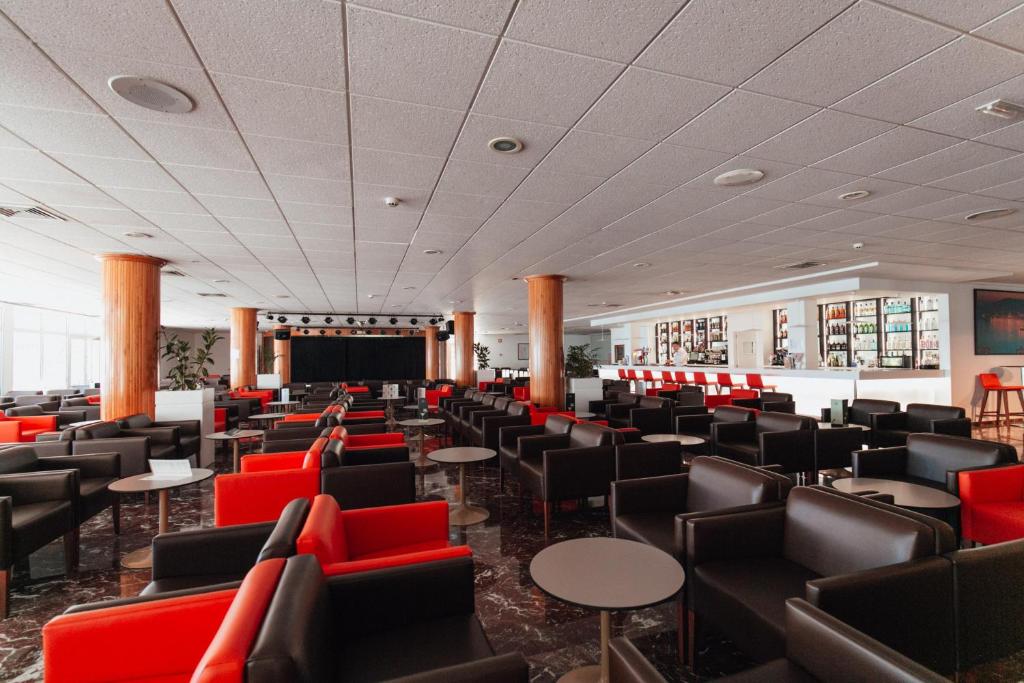 Mūsdienīgs bārs ar melniem un sarkaniem krēsliem, plašu telpu un skatu uz skatuvi. Ideāla vieta relaksācijai un izklaidei.