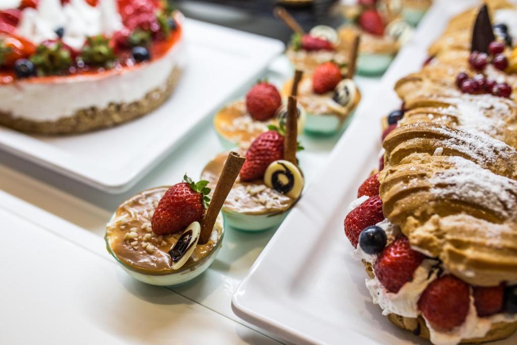 Svaigu un saldu konditorejas izstrādājumu kolekcija, tostarp krēmveida kūka ar augļiem un mini deserti ar zemenēm un šokolādes rotājumiem.