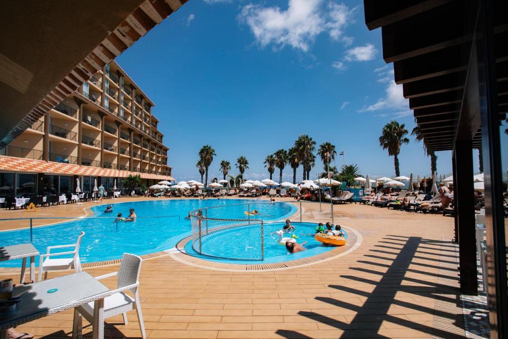 Vasaras brīvdienu kūrorts ar peldbaseinu, palmām un viesnīcu, kur cilvēki atpūšas un izbauda sauli. Ideāla vieta relaksācijai un izklaidei.