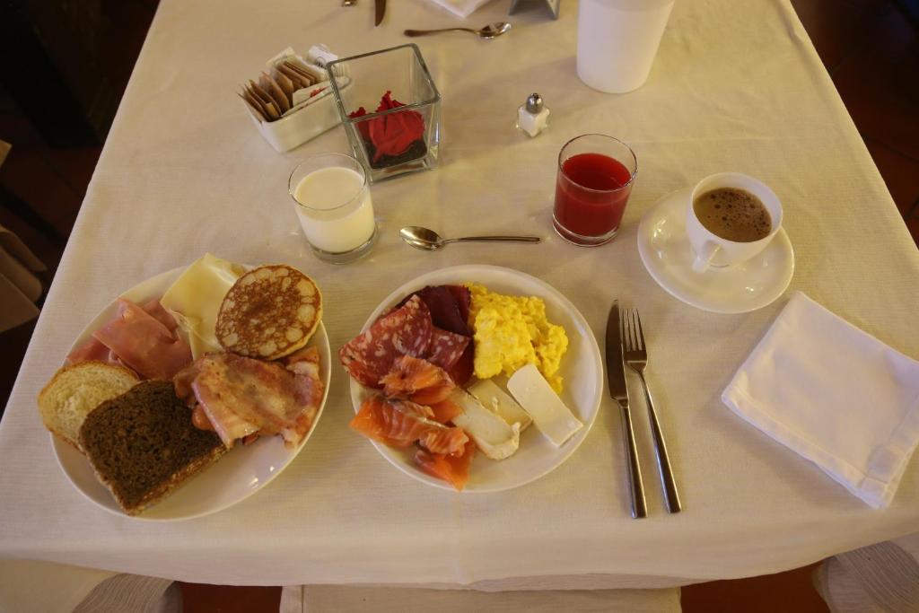 Bagātīga brokastu galds ar dažādiem gaļas un sieru izstrādājumiem, maizi, omleti un dzērieniem, tostarp kafiju un sulu. Ideāls sākums dienai!