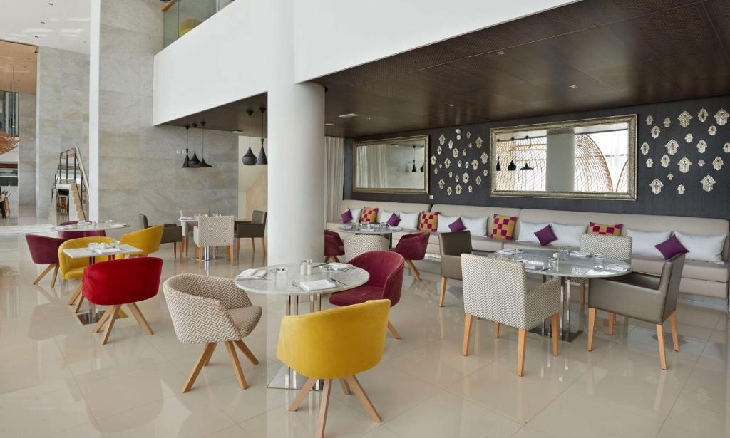 Mūsdienīgs restorāns ar stilīgām krāsainām mēbelēm un elegantu interjeru, kas piedāvā patīkamu vidi ēdienreižu baudīšanai. Gaisma un telpas plānojums rada modernu un aicinošu atmosfēru.