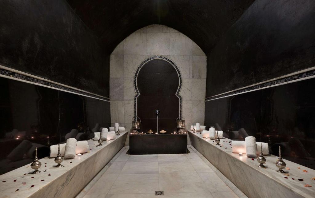 Elegants un mierīgs tvaika pirts interjers ar melnām sienām, marmora virsmām un dekoratīvām lampām. Uz galda izvietoti ziedlapiņas un sveces, radot relaksējošu atmosfēru.