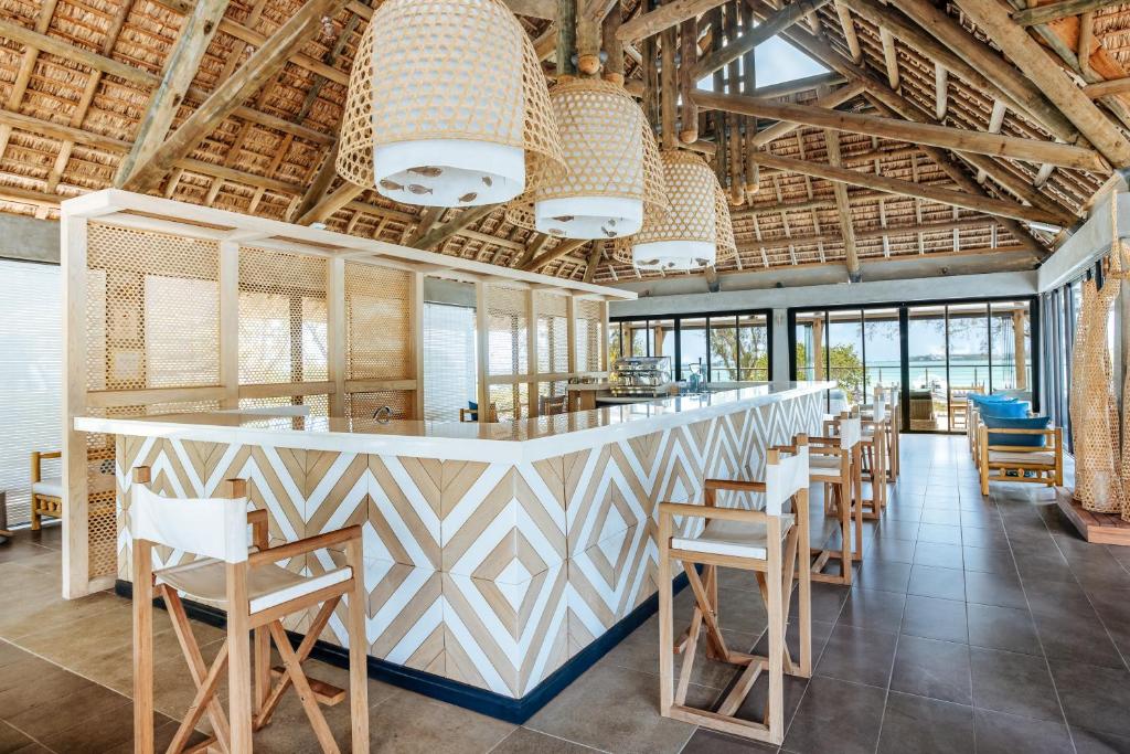 Mūsdienīgs bārs ar elegantu dizainu, koka detaļām un plašiem logiem, kas piedāvā skatu uz pludmali. Interjers ir gaišs un atvērts, radot relaksētu atmosfēru.