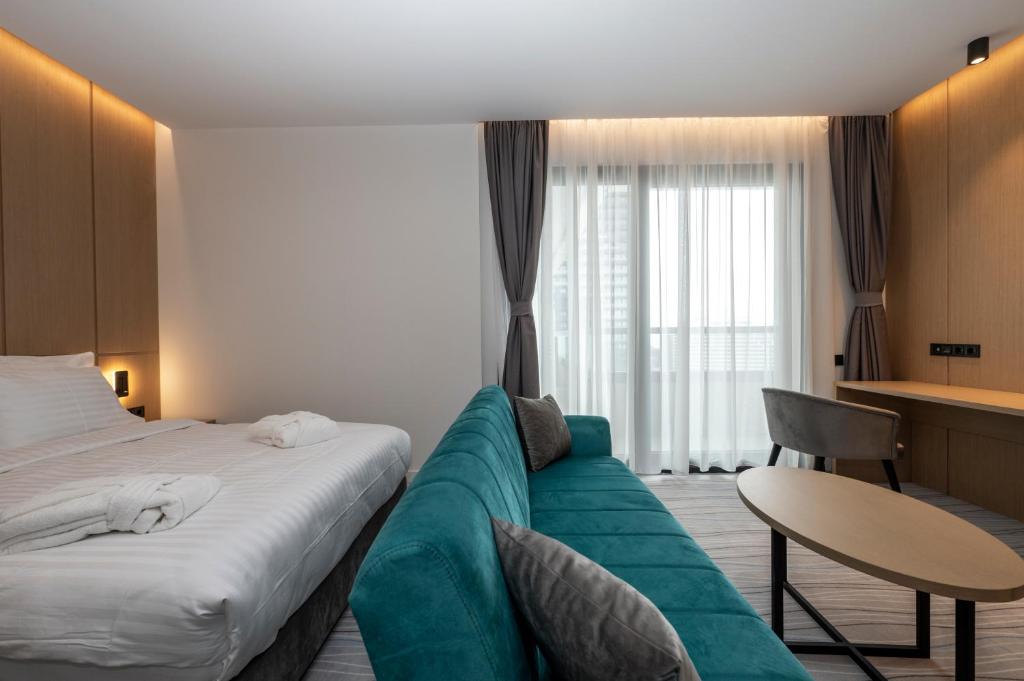 Mūsdienīgs viesnīcas numurs ar divguļamo gultu, dīvānu un darba galdu. Lieli logi ar caurspīdīgām aizkariem nodrošina dabisko apgaismojumu.