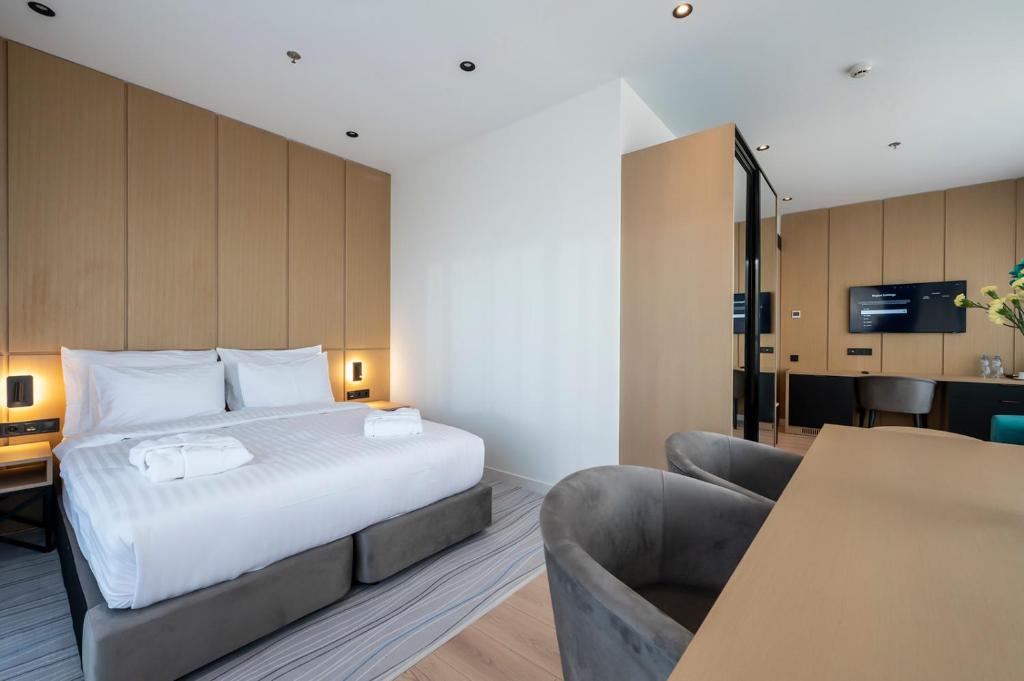 Mūsdienīga viesnīcas numura iekārtojums ar divguļamo gultu, koka sienām un ērtu darba vietu. Telpa ir gaiša un eleganta, ideāli piemērota atpūtai vai darba braucieniem.