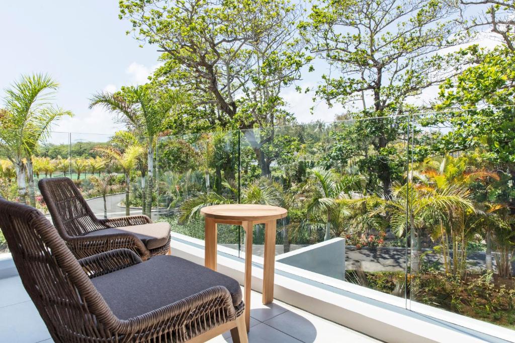 Mūsdienīga terase ar divām ērtām krēsliem un koka galdu, no kuras paveras skats uz zaļojošu ainavu un kokiem. Ideāla vieta relaksācijai dabas vidē.