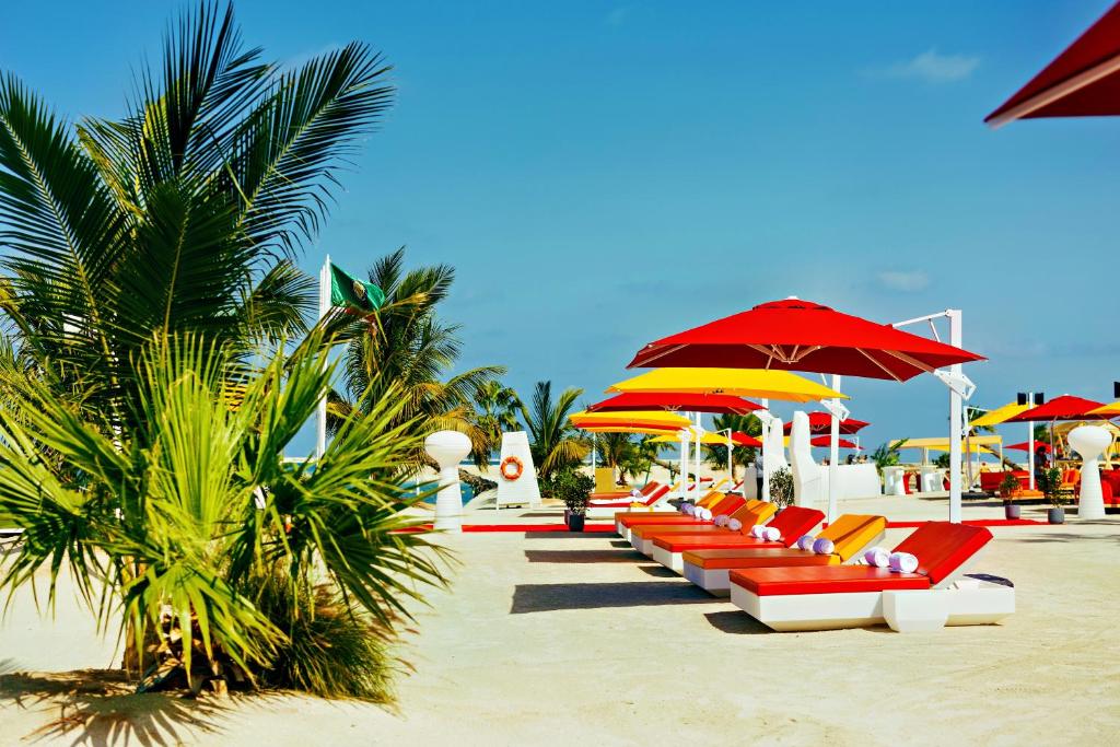 Voco Monaco Dubai pludmales zona ar krāsainiem saulessargiem