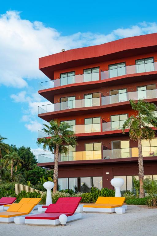 Voco Monaco Dubai viesnīca ar krāsainiem sauļošanās krēsliem pie baseina.