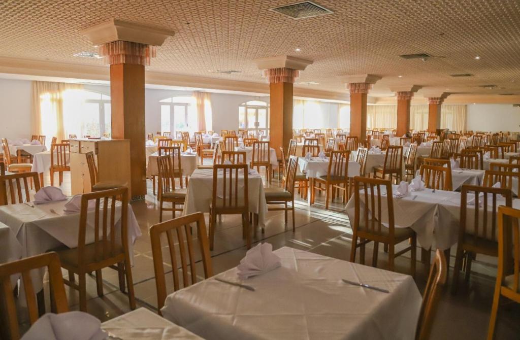 Liela, gaiša restorāna telpa ar daudzām galdiem un krēsliem, izvietotiem simetriski. Uz galdiem ir balti galdauti un salvetes, radot elegantu atmosfēru.
