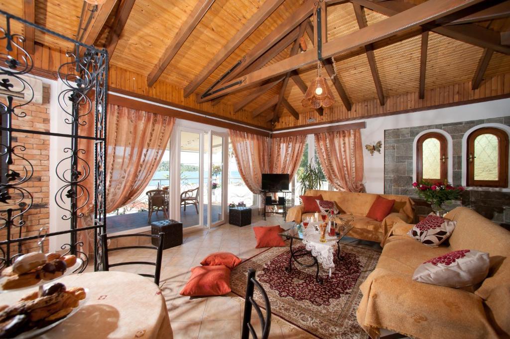 Mūsdienīga viesistaba ar koka griestiem, mīkstām mēbelēm un elegantiem aksesuāriem, kas rada mājīgu atmosfēru. Lielie logi nodrošina dabīgu apgaismojumu un skatu uz ārpusi.