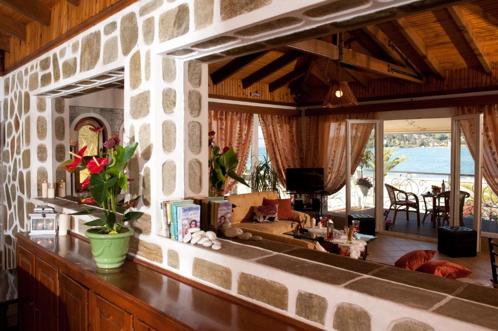 Mūsdienīga viesistaba ar akmens sienām, kurā ir augu kompozīcija un ērti mēbeļu izkārtojumi, kas sniedz skatu uz ūdeni. Interjers apvieno dabiskos elementus un eleganci.