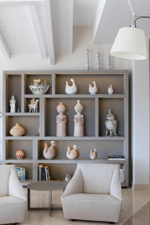 Mākslinieciska viesnīcas Cala Cuncheddi interjera siena ar dekoratīviem priekšmetiem.