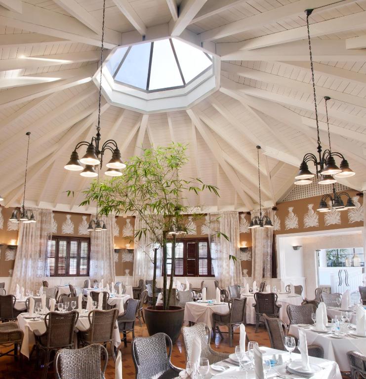 Elegants restorāns ar apaļu jumtu un dabīgu apgaismojumu, kas rada patīkamu atmosfēru. Galdi ir eleganti klāti, ar ziediem un galda piederumiem.