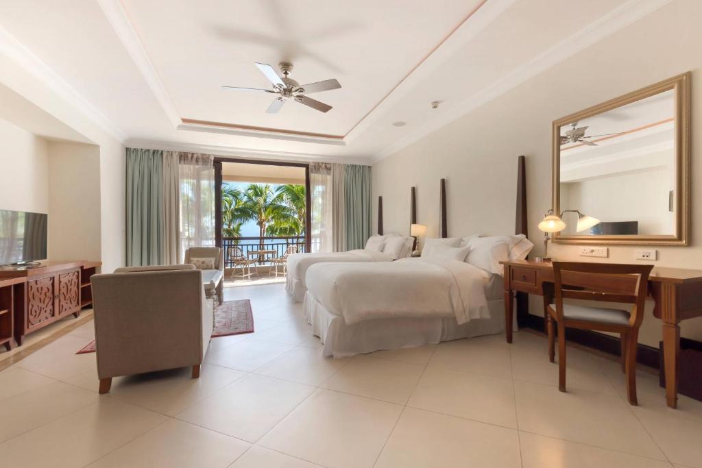 Mūsdienīgs viesnīcas numurs ar divām gultām, ērtu atpūtas zonu un panorāmas skatu uz palmu dārzu. Gaisīgs interjers ar dabīgu apgaismojumu un stilīgu mēbelējumu.