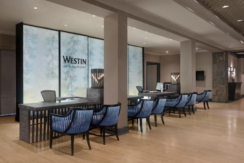 Mūsdienīgs viesnīcas reģistratūras interjers ar elegantām mēbelēm un gaišu apgaismojumu, kas rada siltu un aicinošu atmosfēru.