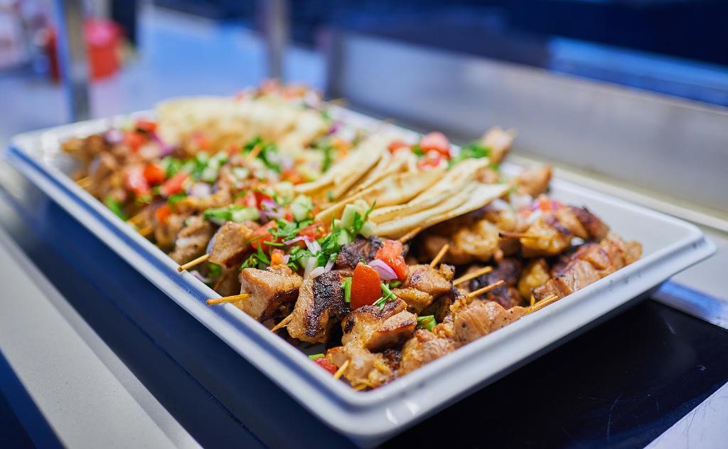 Garšīgus grilētus kebabus uz šķīvja ar dārzeņu salātiem un plānām tortiljām. Ideāls ēdiens svinībām vai piknikam.