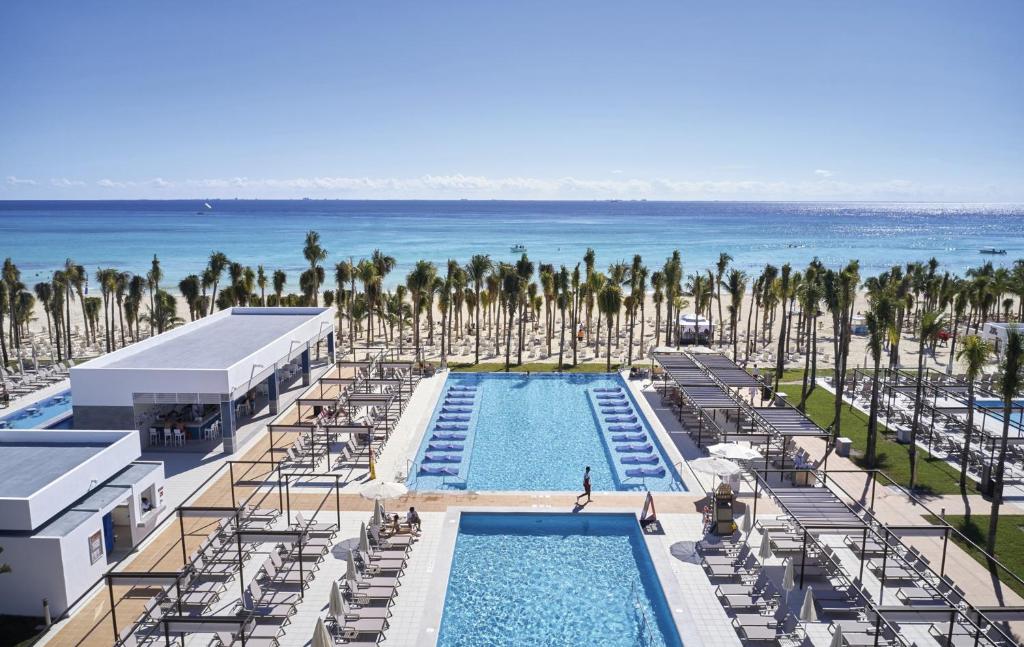 Viesnīcas baseins ar palmām un skatu uz jūru, kas izveido relaksējošu atmosfēru. Ideāla vieta atpūtai pie ūdens un saules.