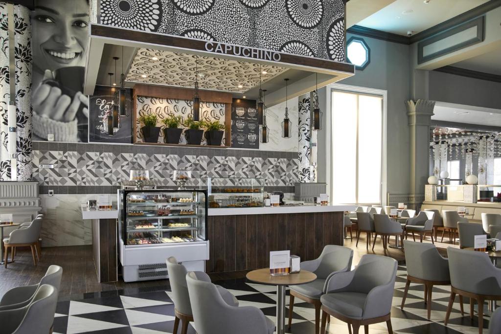 Mūsdienīgs kafejnīcas interjers ar elegantu dekoru, tostarp ģeometriskiem rakstiem un augiem, un kafejnīcas letes skatījums. Ideāla vieta relaksācijai un kafijas baudīšanai.