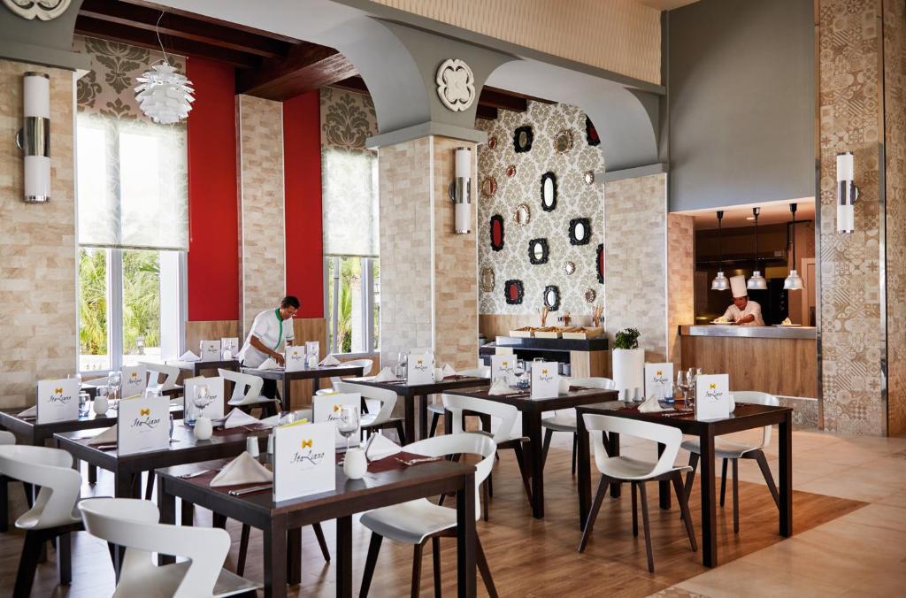 Moderns restorāns ar elegantiem galdiem un krēsliem, apkalpojošs personāls un stilīga dekorācija. Gaisīga atmosfēra ar dabīgu apgaismojumu un mūsdienīgu dizainu.