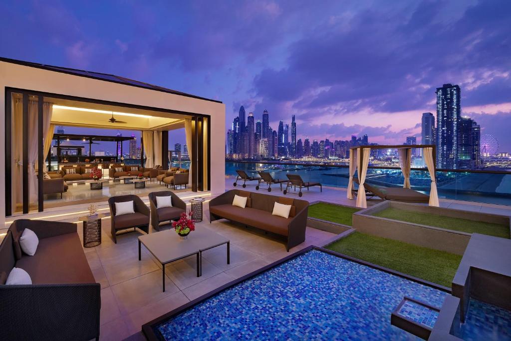 Moderns jumta terases dizains Dubaijā ar elegantiem mēbelēm un skatu uz pilsētas panorāmu saulrieta laikā. Terasē ir maza baseina zona un zāle ar zaļumiem, radot relaksējošu atmosfēru.