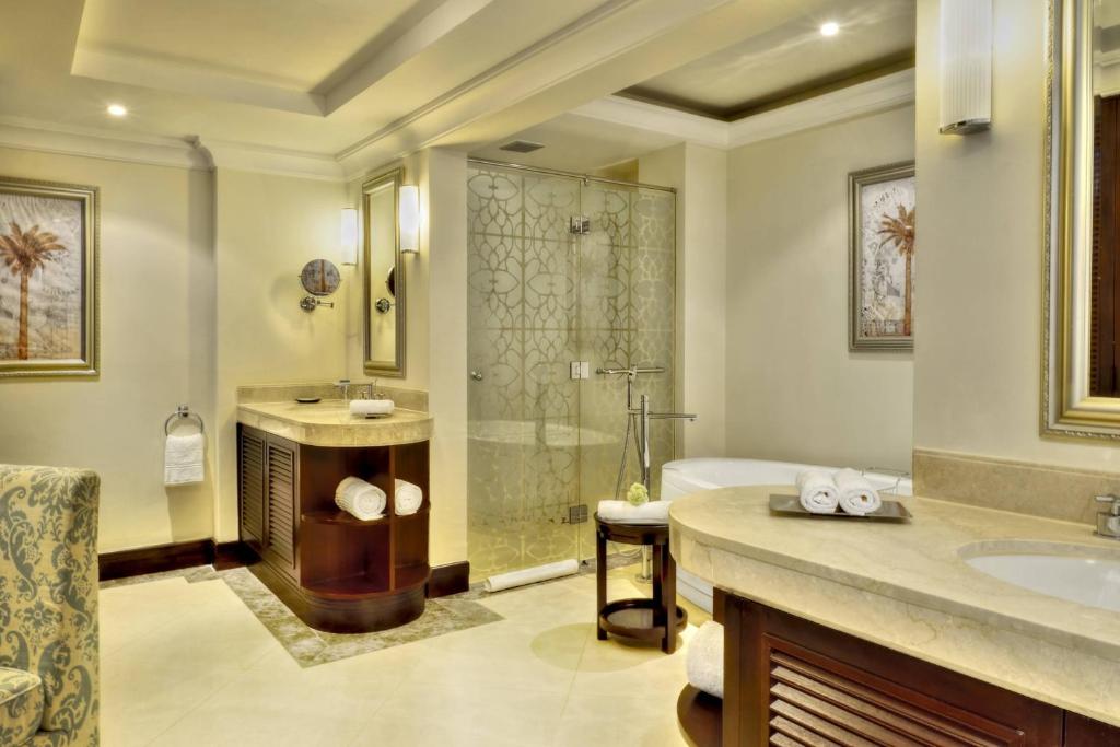 Mūsdienīgs vannas istabas interjers ar dušas kabīni, vannu un elegantu izkārtojumu, kurā ir akcenti ar palmām un stilīgiem sanitārajiem izstrādājumiem.