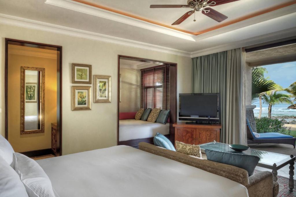 Mūsdienīgs viesnīcas numurs ar plašu logu, no kura paveras skats uz pludmali, un elegantu interjeru, kas ietver komfortablu gultu un televizoru. 