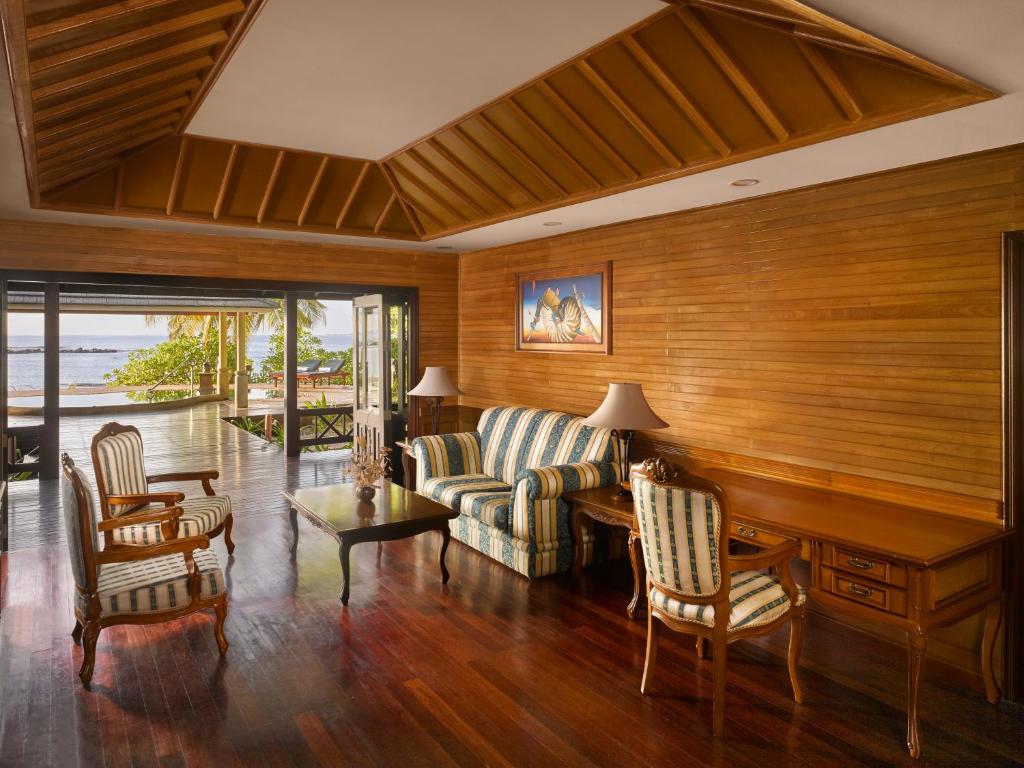 Mūsdienīgs viesistabas interjers ar koka apdari, ērtiem dīvāniem un galdu, kas piedāvā skatu uz jūru. Telpa ir piepildīta ar dabīgu gaismu un relaksējošu atmosfēru.