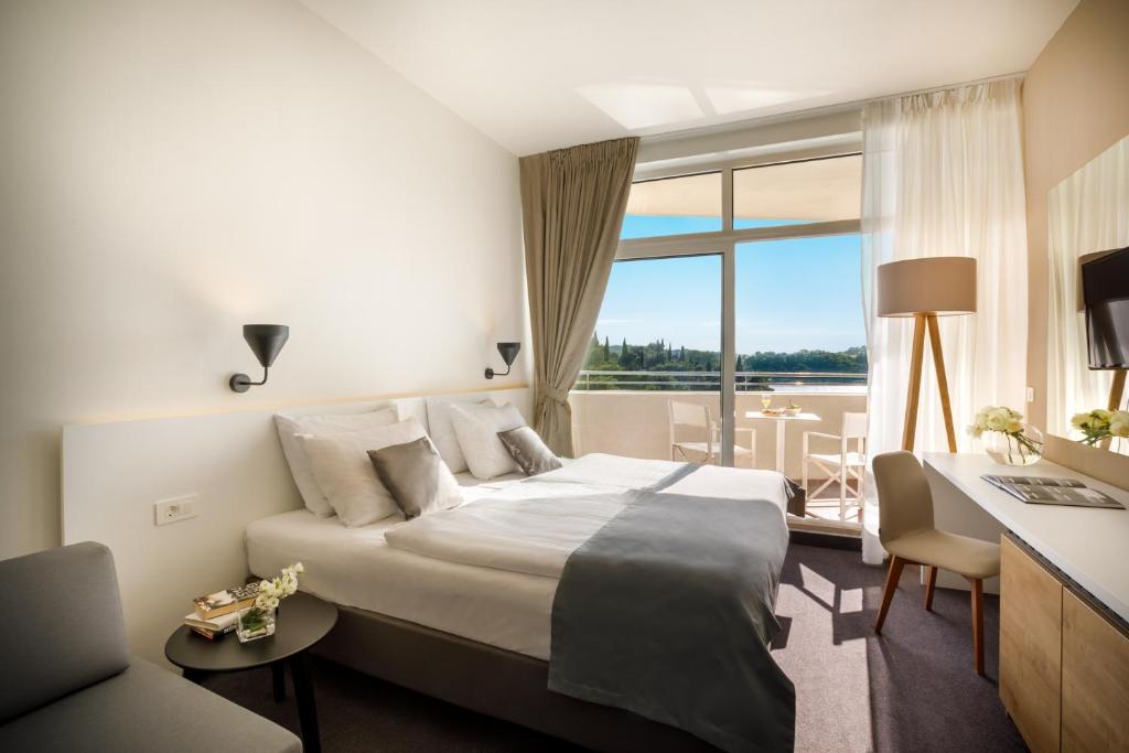 Mūsdienīgs viesnīcas numurs ar gultu, ērtu atpūtas stūrīti un balkonu, no kura paveras skats uz dabu. Interjers ir gaišs un elegants, radot komfortablu atmosfēru.