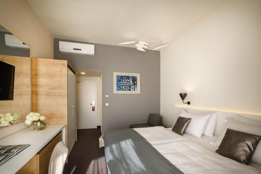 Mūsdienīgs viesnīcas numurs ar divguļamo gultu, televizoru un rakstāmgaldu, kā arī dekoratīvām gleznām pie sienām. Interjers ir gaišs un elegants, radot patīkamu atmosfēru.