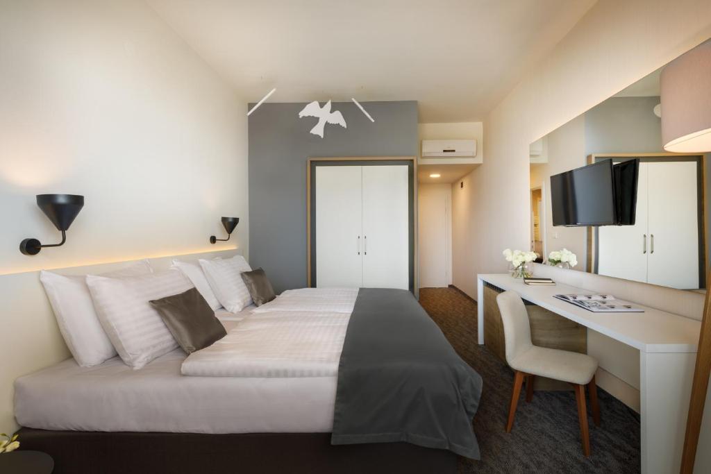 Mūsdienīgs viesnīcas numurs ar divām gultām, gaišām sienām un stilīgu interjeru, kas ietver rakstāmgaldu un televizoru. Numurā ir arī dekoratīvas gaismas un ziedi, radot patīkamu atmosfēru.