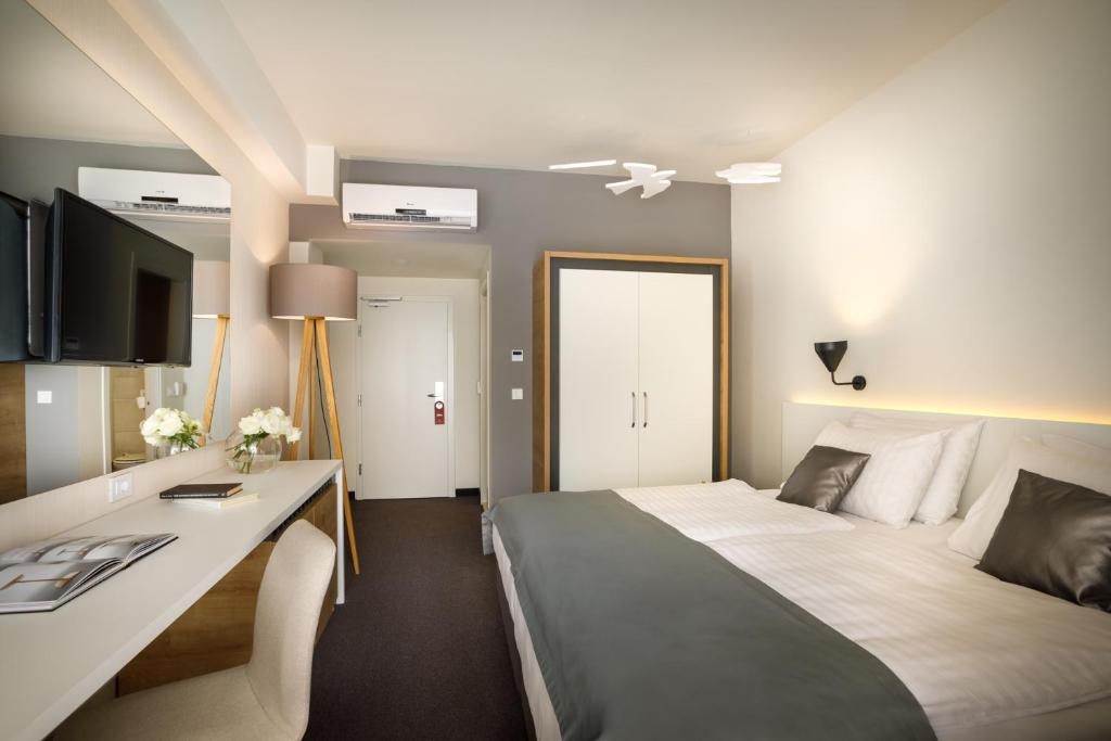 Mūsdienīga viesnīcas numura iekārtojums ar ērtu gultu, rakstāmgaldu un televizoru. Gaismas un krāsas rada patīkamu atmosfēru.