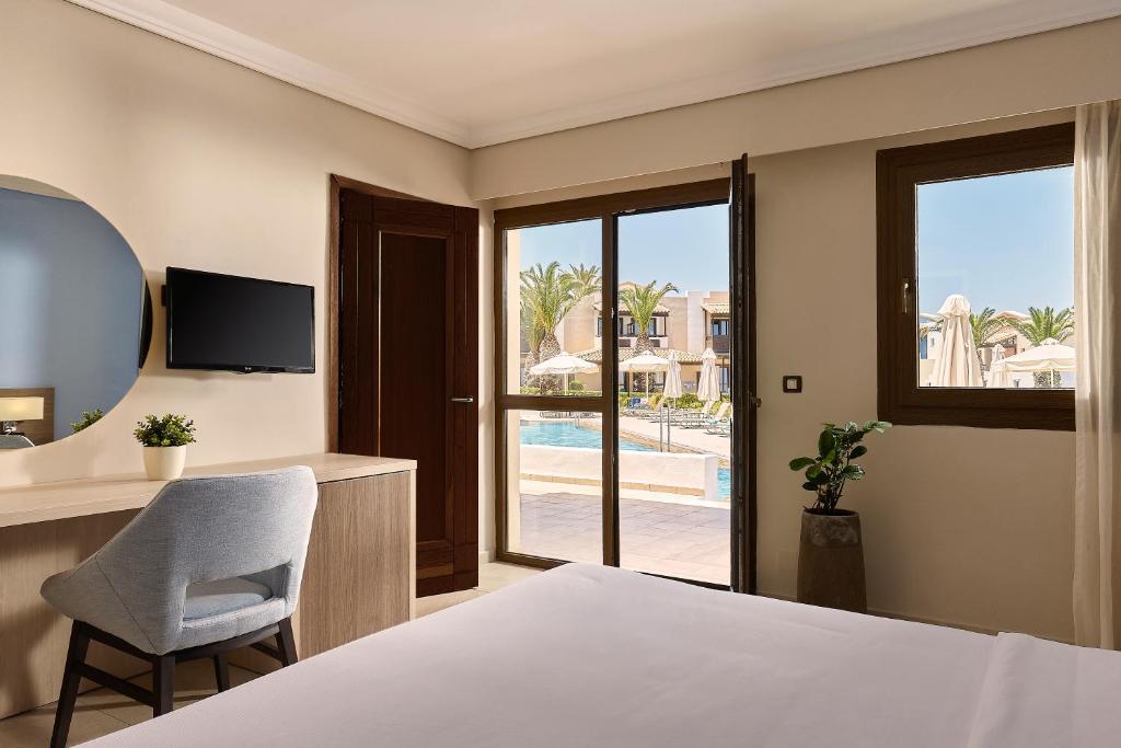 Mūsdienīgs numurs viesnīcā Knossos Royal ar skatu uz baseinu.