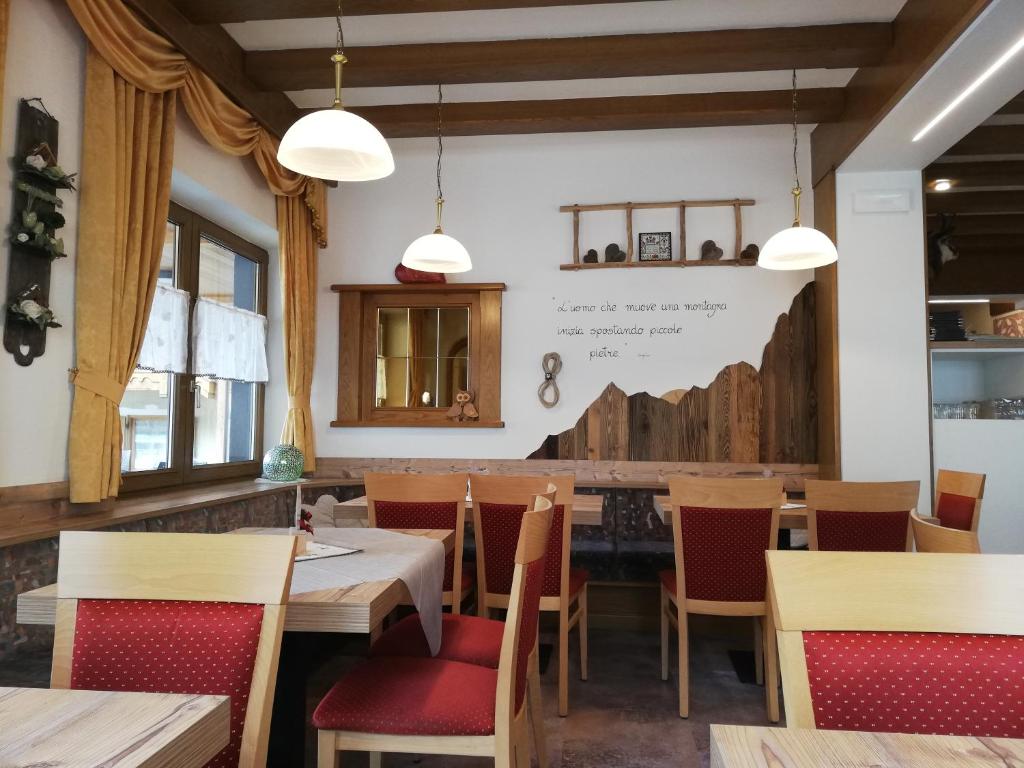 Gaiša un mājīga kafejnīca ar koka mēbelēm un siltām krāsām, kurā ir redzami logi ar aizkariem un dekoratīvi elementi uz sienām.