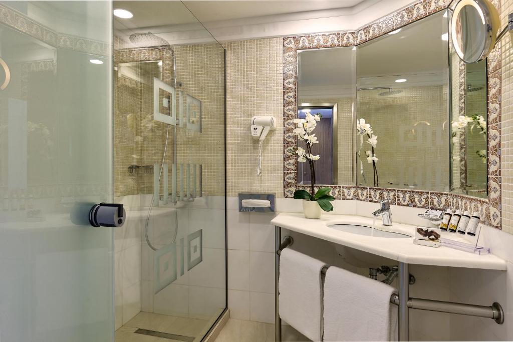 Mūsdienīgs vannas istabas interjers ar stikla dušu viesnīcā Knossos Royal