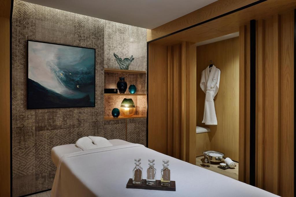 Mūsdienīgs spa telpas interjers ar masāžas galdu, dekoratīviem elementiem un mākslas darbu uz sienas, radot relaksējošu atmosfēru.