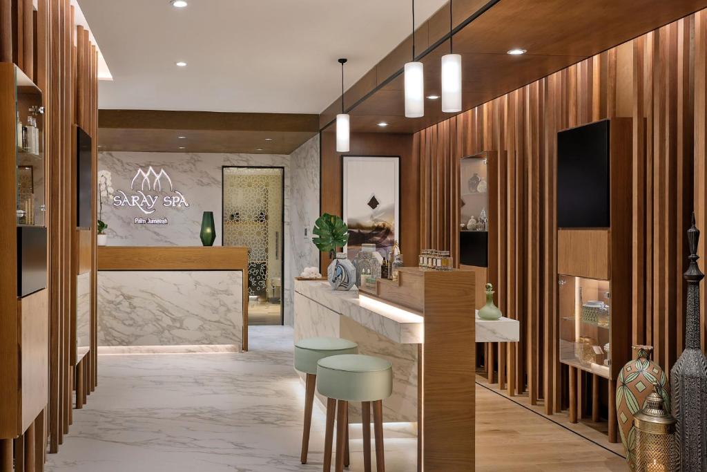 Skaista mūsdienīga spa recepcija ar koka un marmora elementiem, kurā ir gaismas, dekoratīvi objekti un relaksējoša atmosfēra.