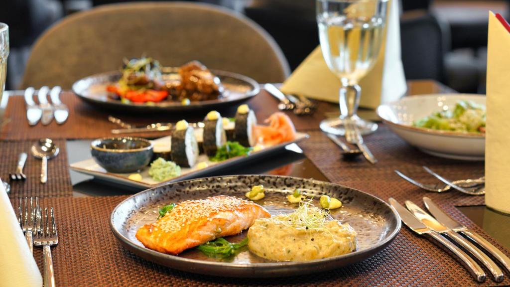Gourmet ēdienu servēšana ar grilētu lasi un garnelēm, papildināta ar rīsu un dārzeņu garnējumu. Elegants restorāna galdiņš ar izsmalcinātiem galda piederumiem un dzērieniem.